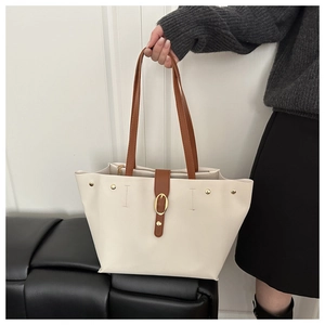 Dettaglio di una grande borsa tote crema con cinturini in pelle marrone e fibbia oro