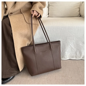 Close-up of deep brown tote bag with premium lychee grain texture and leather straps