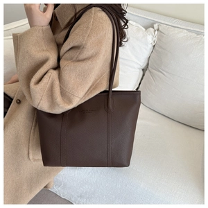 Detail of a vintage large brown leather shoulder bag on a light wool coat outfit