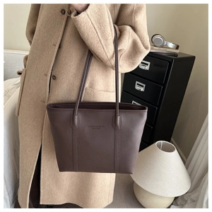 Detailed macro view of deep brown tote bag featuring textured litchi grain leather finish