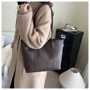 Detail of dark brown lychee texture leather tote bag with embossed fashion text detail