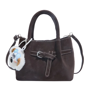 Dark brown suede bucket bag with white stitching and cute puppy pendant accessory
