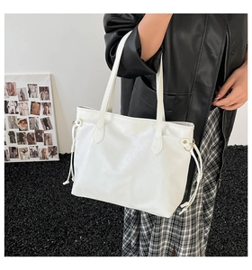 Detail of white tote bag with embossed texture and drawstring side on a shoulder model