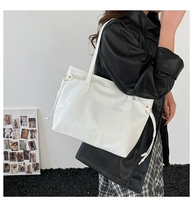 Close-up of white PU leather tote bag featuring unique cartoon embossed textures and gold hardware