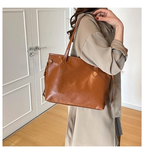 Detail of caramel brown tote bag featuring textured cartoon embossing and slim shoulder straps