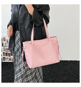 Detail of pink faux leather tote bag featuring embossed letters and side drawstrings