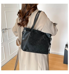 Detail of black embossed tote bag with geometric patterns shown on a model