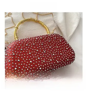 Dettaglio borsa da sera rossa con strass, manico dorato a forma di bambù e tracolla a catena