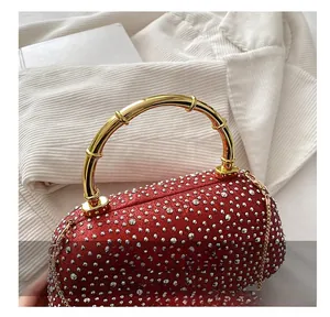 Dettaglio della borsa da sera rossa con strass, manico in bambù dorato e tracolla a catena