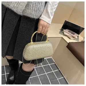 Dettaglio dell'elegante borsa da sera dorata con strass e manico in bambù con catena