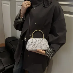 Dettaglio della borsa da sera bianca con strass luccicanti e manico in bambù dorato