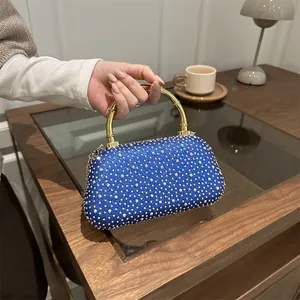 Dettaglio borsa da sera blu con strass e elegante manico in metallo dorato bambù