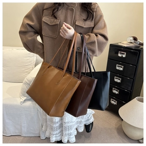 Three minimalist leather tote bags in brown, coffee, and black shown in a lifestyle setting