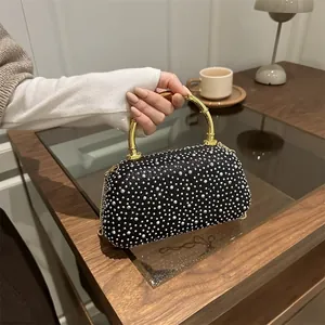Dettaglio di borsa da sera nera con strass argento e manico in bambù dorato