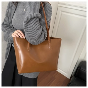Detailed side view of a large brown tote bag worn with a casual commute outfit