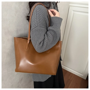 Close-up of a brown leather tote bag showing fine stitching and durable shoulder straps
