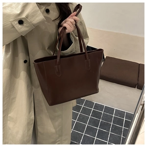 Detail of dark brown leather tote bag with slim shoulder straps for office commute style