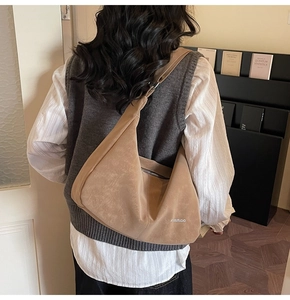 Detail view of khaki soft leather tote featuring a side metal zipper and brand logo