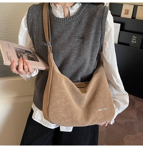 Detail of khaki suede crossbody bag with letter print styled with casual knit vest