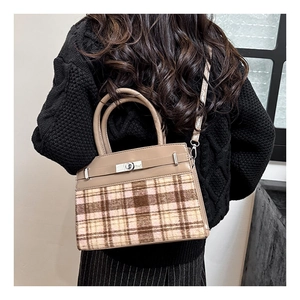 Detailopname van de wollen textuur en de leren riem van de vintage geruite handtas