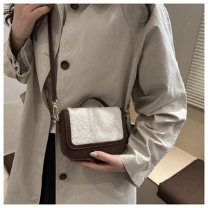Detail of vintage faux shearling and brown leather saddle bag on a trench coat model