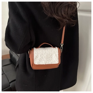 Close-up of vintage brown leather bag with white faux fur flap on black wool coat