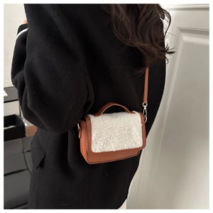 Detail of a brown leather saddle bag with white shearling trim on a model's shoulder