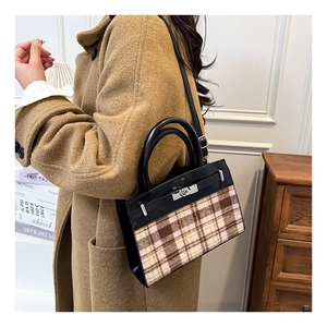 Detail van retro geruite handtas met zilveren sluiting gedragen op een camelkleurige jas
