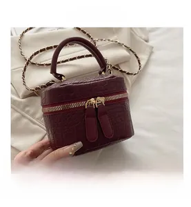 Dettaglio macro della borsa quadrata bordeaux con stampa coccodrillo e finiture dorate