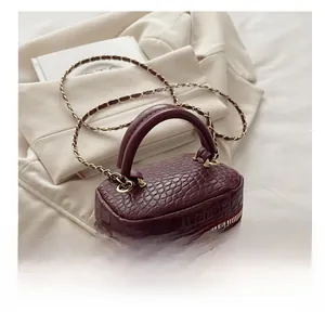 Dettaglio borsa vanity bordeaux effetto coccodrillo con zip dorata e tracolla intrecciata