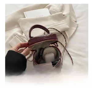 Vista interna che mostra la capacità di una mini borsa rotonda in pelle goffrata rosso scuro