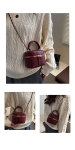 Detail of burgundy crocodile pattern mini box bag with gold zipper and chain strap