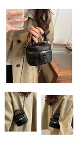 Close-up of black crocodile texture mini handbag with gold chain strap and dual zippers