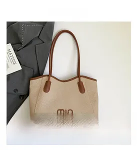 Detail of woven bucket bag with contrast leather handles and minimalist logo