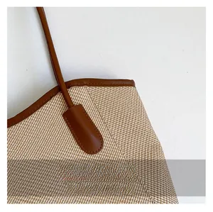 Detail shot of woven fabric texture and premium brown leather trim on the tote bag