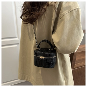 Dettaglio borsa quadrata nera a coccodrillo con tracolla a catena su trench beige