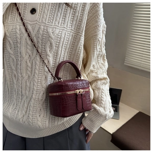 Dettaglio della mini borsa a scatola bordeaux con trama a coccodrillo indossata da una modella