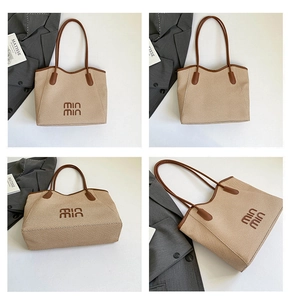Detail view of woven tote bag with brown leather straps and embroidered min min text
