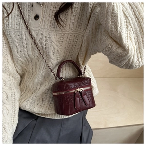 Detail of burgundy crocodile-embossed box bag with chain strap and gold hardware