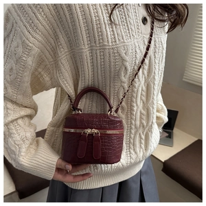 Close-up of burgundy crocodile pattern mini box bag with gold chain strap on model