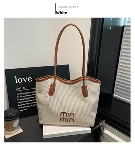 Detail of cream woven tote bag with brown leather handles and 3D logo on books