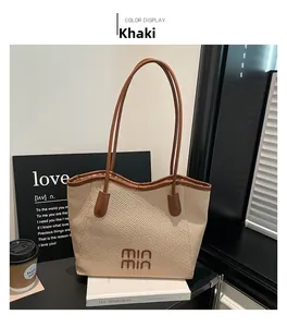Detail view of khaki woven tote bag with brown leather handles and embossed branding