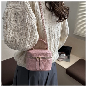 Close-up of pink mini bucket bag with crocodile pattern and gold zipper detail