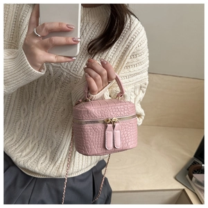 Detail of pink croc-pattern mini box bag with gold double zippers and chain strap