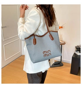 Detailed embroidery of brand logo on the blue woven texture and leather tote bag