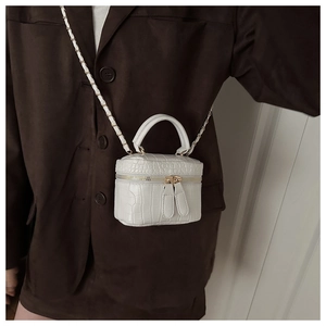 Close-up of white croc-embossed mini box bag with golden chain and zipper details