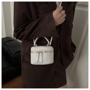 Detail of cream mini box bag with crocodile embossed texture and gold chain strap