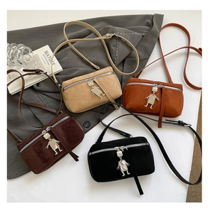 Detailed flat lay of suede mini crossbody bags in four colors with robot charms