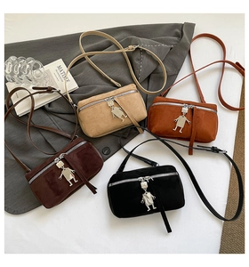 Top view of suede shoulder bags in four colors with robotic metal charms and silver zippers