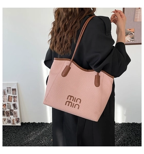 Pink woven tote bag with brown leather handles worn by model in minimalist studio